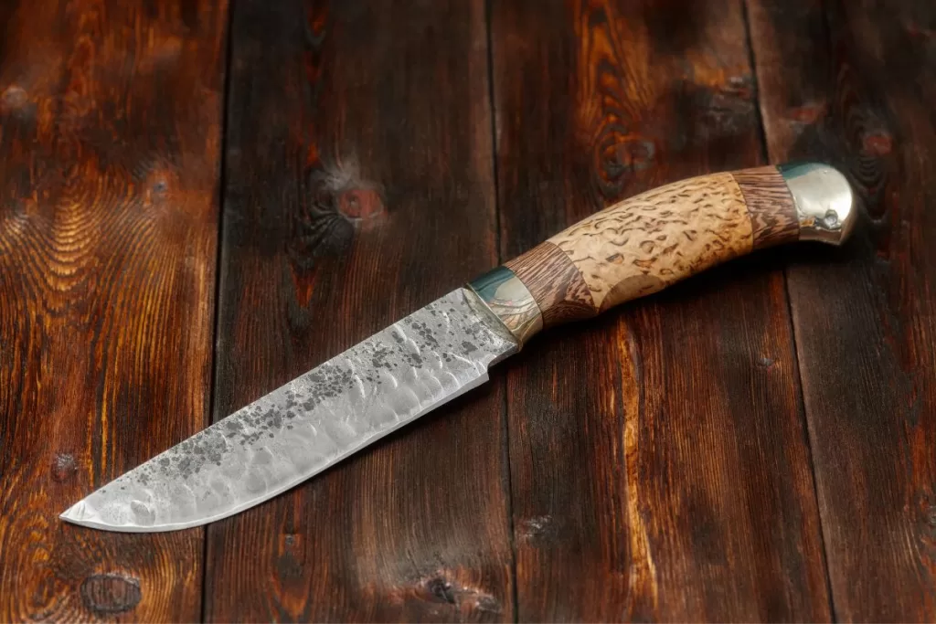 A beautiful and sharp Damascus steel chef's knife on a wooden cutting board.